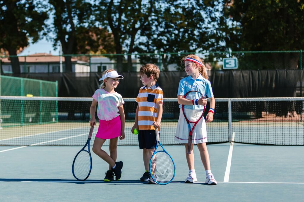 Three children having fun with tennis rackets on a sunny day.